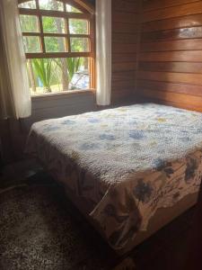a bed in a room with a window at Chalé aconchegante in Itu