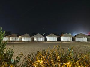 - une rangée de tentes sur une plage la nuit dans l'établissement Awar Desert Safari, à Jaisalmer