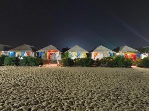 a row of tents on a sandy beach at night at Awar Desert Safari in Jaisalmer