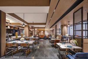 a restaurant with tables and chairs in a room at Novotel Nantong Center in Nantong