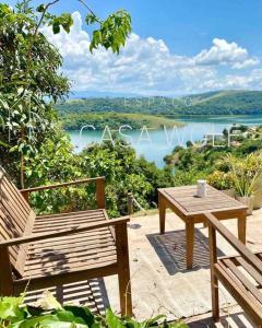 mesa de madera y banco con mesa y vistas al lago en Paraíso: Natureza, Piscina, Churrasqueira e Wi-Fi, en Igaratá