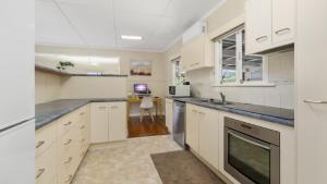 a kitchen with white cabinets and a sink at Kooringal Cottage - Home By The Sea in Woorim