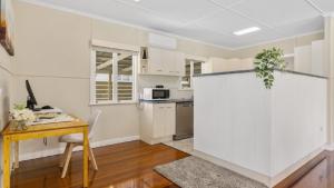 a kitchen with white cabinets and a wooden table at Kooringal Cottage - Home By The Sea in Woorim