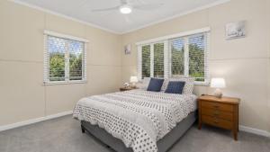 a white bedroom with a bed and two windows at Kooringal Cottage - Home By The Sea in Woorim +11 photos
