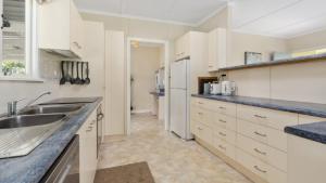 a kitchen with white cabinets and blue counter tops at Kooringal Cottage - Home By The Sea in Woorim