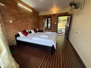a bedroom with a large bed in a brick wall at Little Pilgrim Family Lodge in Pokhara
