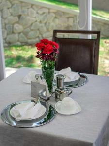 una mesa con platos y un jarrón de flores rojas en CASONA LA MARQUEZA - Hotel Boutique en Tinquipaya