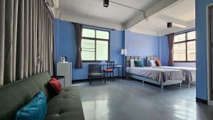 a bedroom with blue walls and a bed and a couch at HOUSEMODE - BAANYAI @ Wongwian Yai in Bangkok