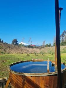 una bañera de madera llena de agua en un campo en Cabaña Puerto Octay, en Puerto Octay