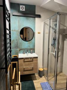 y baño con lavabo y ducha con espejo. en Narciarska6A Apartamenty en Szczyrk