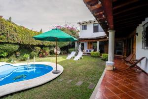 a pool with an umbrella next to a house at Cozy family house I Pool & Bar l Cuernavaca in Cuernavaca