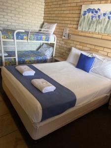 a bed with blue and white pillows on it at Castle Motor Lodge in Bowen