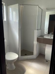 a bathroom with a shower and a toilet and a sink at Castle Motor Lodge in Bowen