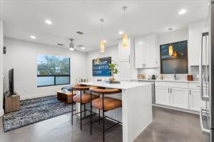 una cocina con armarios blancos y un bar con taburetes en 4 Bedroom-Downtown-Rooftop W Views & Walkable en Austin