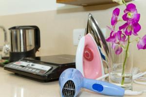 a sink with a phone and a vase with purple flowers at Sanctum Suites Whitefield Bangalore in Bangalore +24 photos