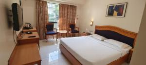 a hotel room with a bed and a table and chairs at The Ambassador Hotel Pune in Pune