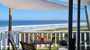 a table on a balcony with a view of the beach at TAKE TWO lovely beach apartment, Great Brak River in Groot Brak Rivier