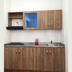 cocina con armarios de madera, fregadero y TV en Apartamentos Amoblados Napoles en Doradal