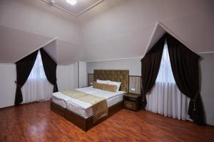 a bedroom with a bed and two windows with curtains at Elite Art Hotel in Tashkent