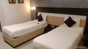 two beds in a hotel room with white sheets at Hotel Sitara Grand L.B. Nagar in Hyderabad