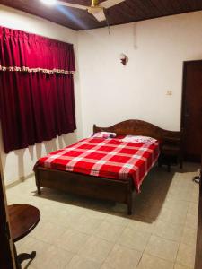 1 dormitorio con 1 cama con manta de cuadros roja en Green nature villa en Hapugala