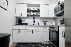 a white kitchen with white cabinets and a sink at Jay's Cozy Escape in Tampa +11 photos
