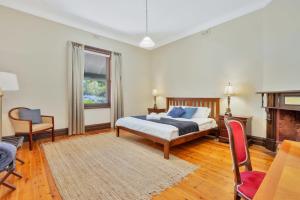 een slaapkamer met een bed en een stoel en een open haard bij Barossa Vineyard Guesthouse in Tanunda