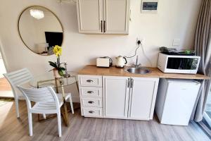 a kitchen with a table and a sink and a microwave at Cottage at 6 on Elba in Paarl
