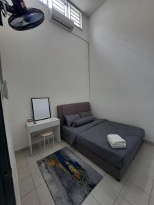 Schlafzimmer mit einem Bett und einem Schreibtisch mit einem Laptop in der Unterkunft D'homestay Parit Buntar in Parit Buntar