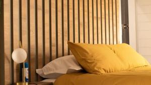 a bed with yellow pillows and a wooden headboard at Leipoldt Self-Catering Apartment in Secunda