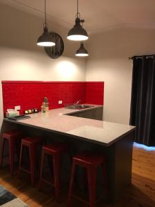 a kitchen with a counter and a red wall at MURRUMBURRAH ARTHOUSE APARTMENTS in Harden +14 photos