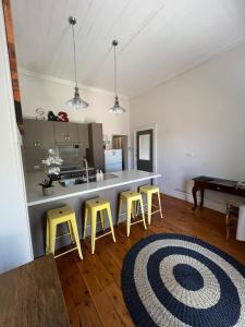 a kitchen with three yellow stools and a counter at MURRUMBURRAH ARTHOUSE APARTMENTS in Harden