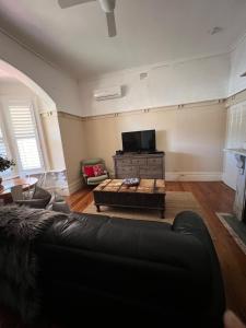 sala de estar con sofá negro y TV en MURRUMBURRAH ARTHOUSE APARTMENTS, en Harden