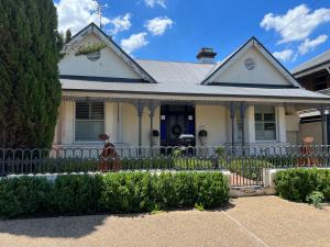 a white house with a fence in front of it at MURRUMBURRAH ARTHOUSE APARTMENTS in Harden