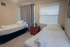 a bedroom with two beds and a window and a dresser at Palm Wave Stays - Central and Cozy Apt in West Palm Beach