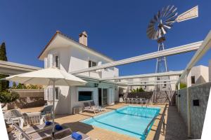 a house with a swimming pool and a windmill at Accomoteleia Crystal Lagoon Villa in Protaras