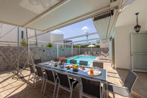 a patio with a table and chairs and a swimming pool at Accomoteleia Crystal Lagoon Villa in Protaras