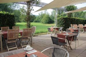 an outdoor patio with tables and chairs and an umbrella at Hotel Auf der Bühn in Malsch