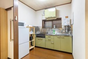 a kitchen with green cabinets and a white refrigerator at 神谷戸建 in Tokyo