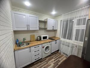 a small kitchen with a sink and a microwave at Однокомнатная квартира in Balqash