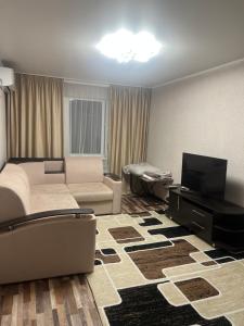 a living room with a couch and a flat screen tv at Однокомнатная квартира in Balqash