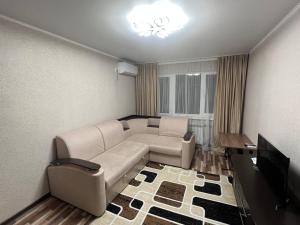 a living room with a couch and a television at Однокомнатная квартира in Balqash