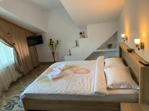 um quarto com uma cama com lençóis brancos e almofadas em Casa Cristian em Sinaia