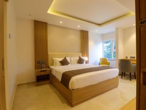 a bedroom with a bed and a desk and a window at Hotel Grand Serene, Mysore in Mysore