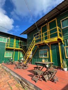 a building with a yellow and green building with picnic tables at Global Lepa Lodge in Semporna