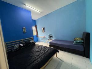 a bedroom with two beds and a blue wall at Nurul Aisyah Homestay in Tanah Rata