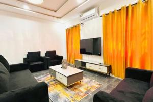 a living room with orange curtains and a television at LES 9 Plurielles T3 KPALIME KOUMA KONDA in Palimé