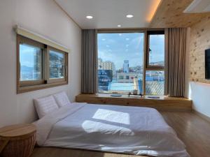 a bedroom with a white bed and a large window at 38th Street Guesthouse in Mokpo