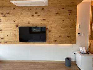 a living room with a flat screen tv on a wooden wall at 38th Street Guesthouse in Mokpo
