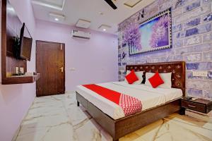1 dormitorio con 1 cama grande con almohadas rojas en OYO Flagship Hotel Sangam Palace, en Bamrauli
